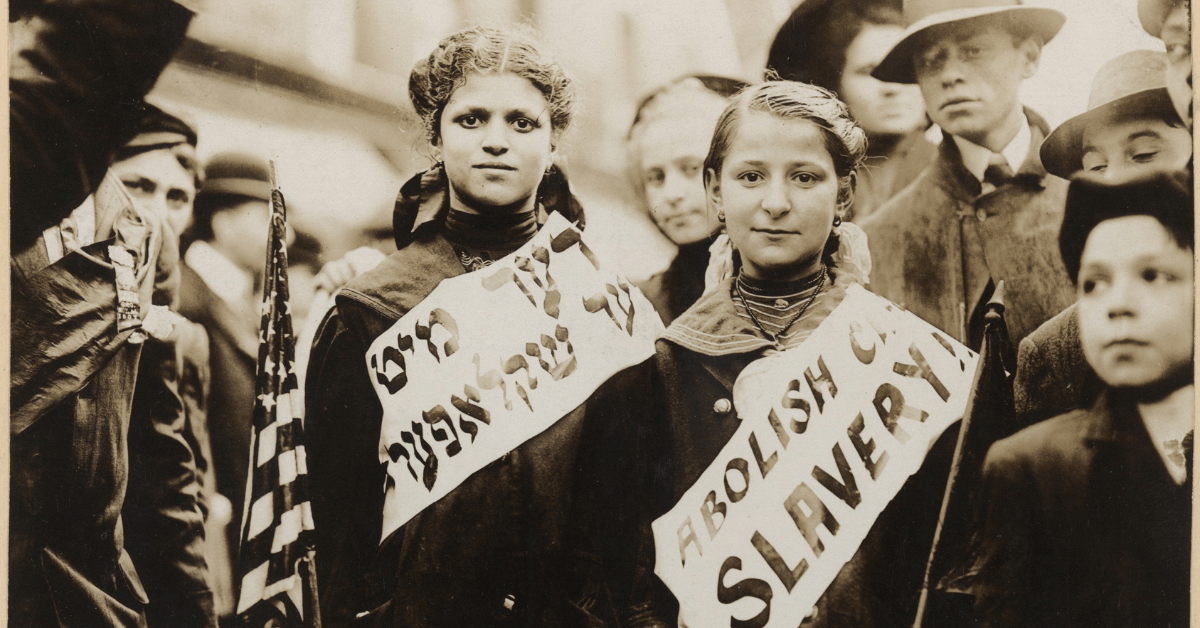 Historic black-and-white photo of two young girls wearing sashes protesting child slavery